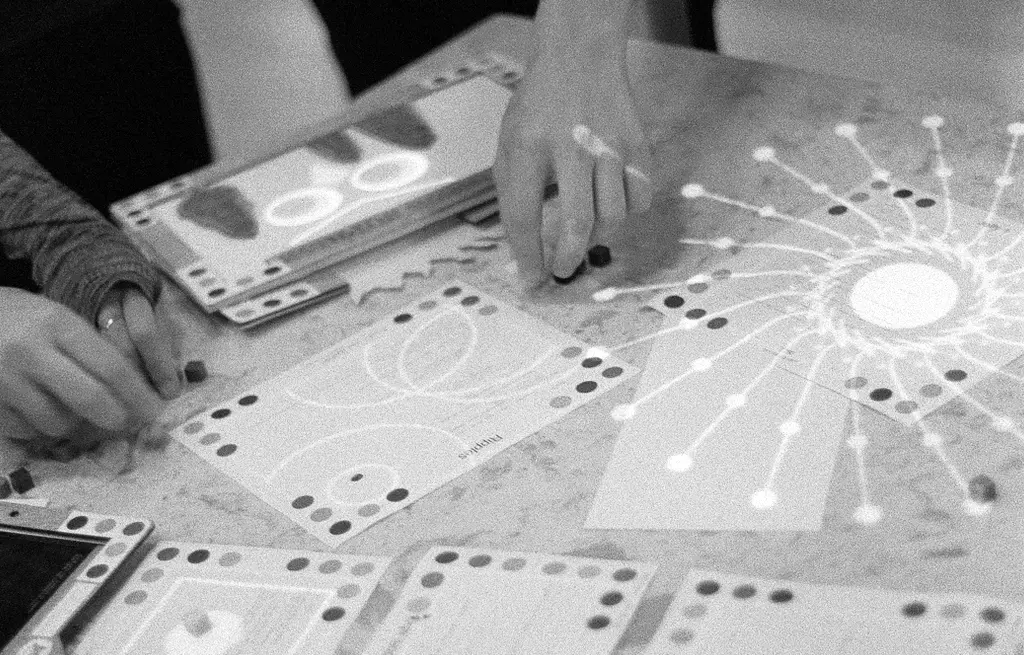 The colored dots around the edges of these pages are read by cameras around the Dynamicland space. Image from the Concord Consortium.